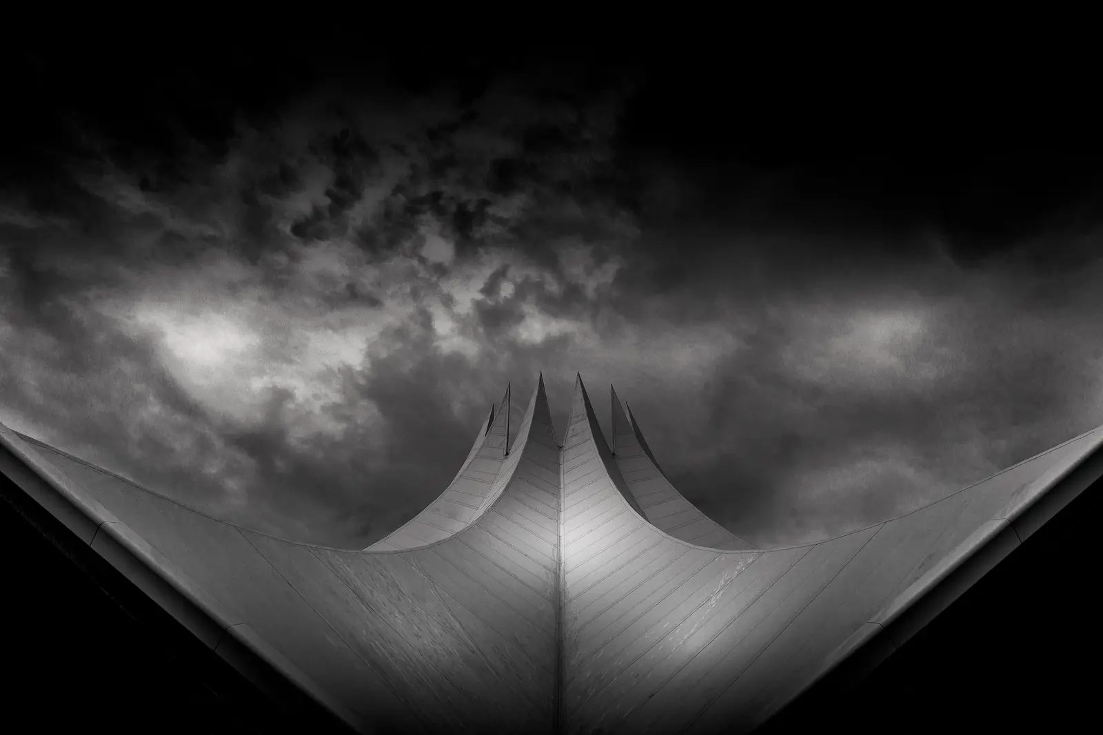 The curved peaks of a tensile roof against a dark sky.